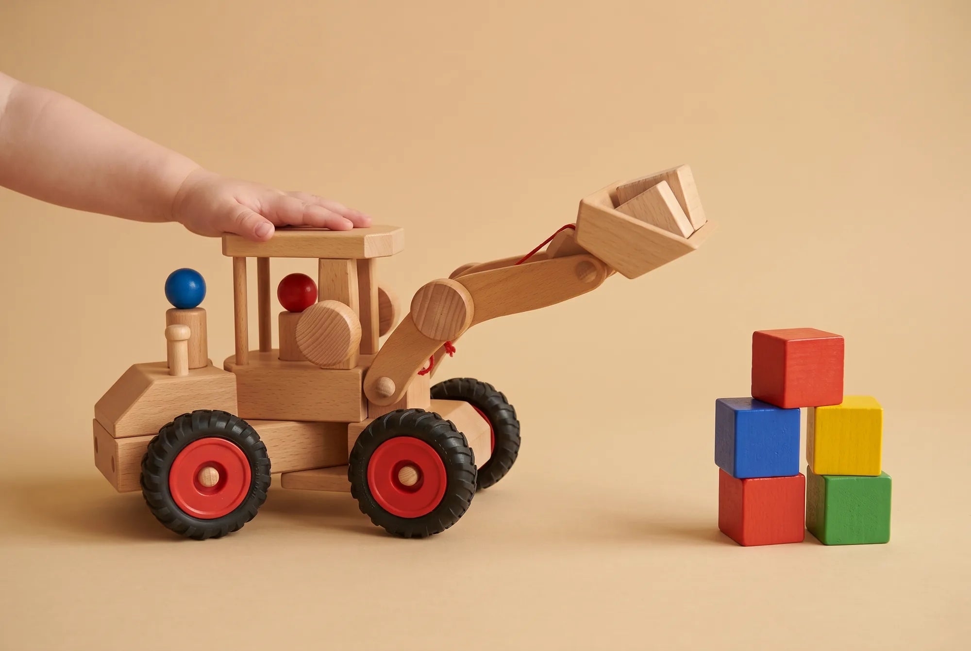 A child’s hand on the Fagus Wheel Loader as it lifts wooden blocks