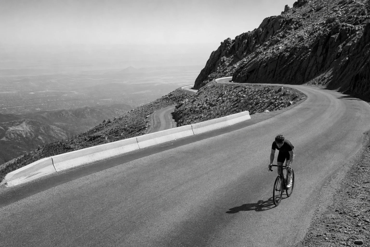 A lone road cyclist climbing a steep mountain switchback