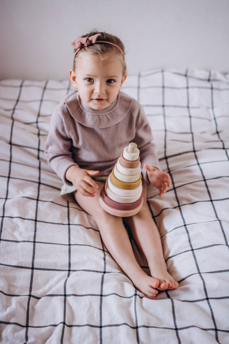 Toddler sitting with the SABO wooden ring stacker