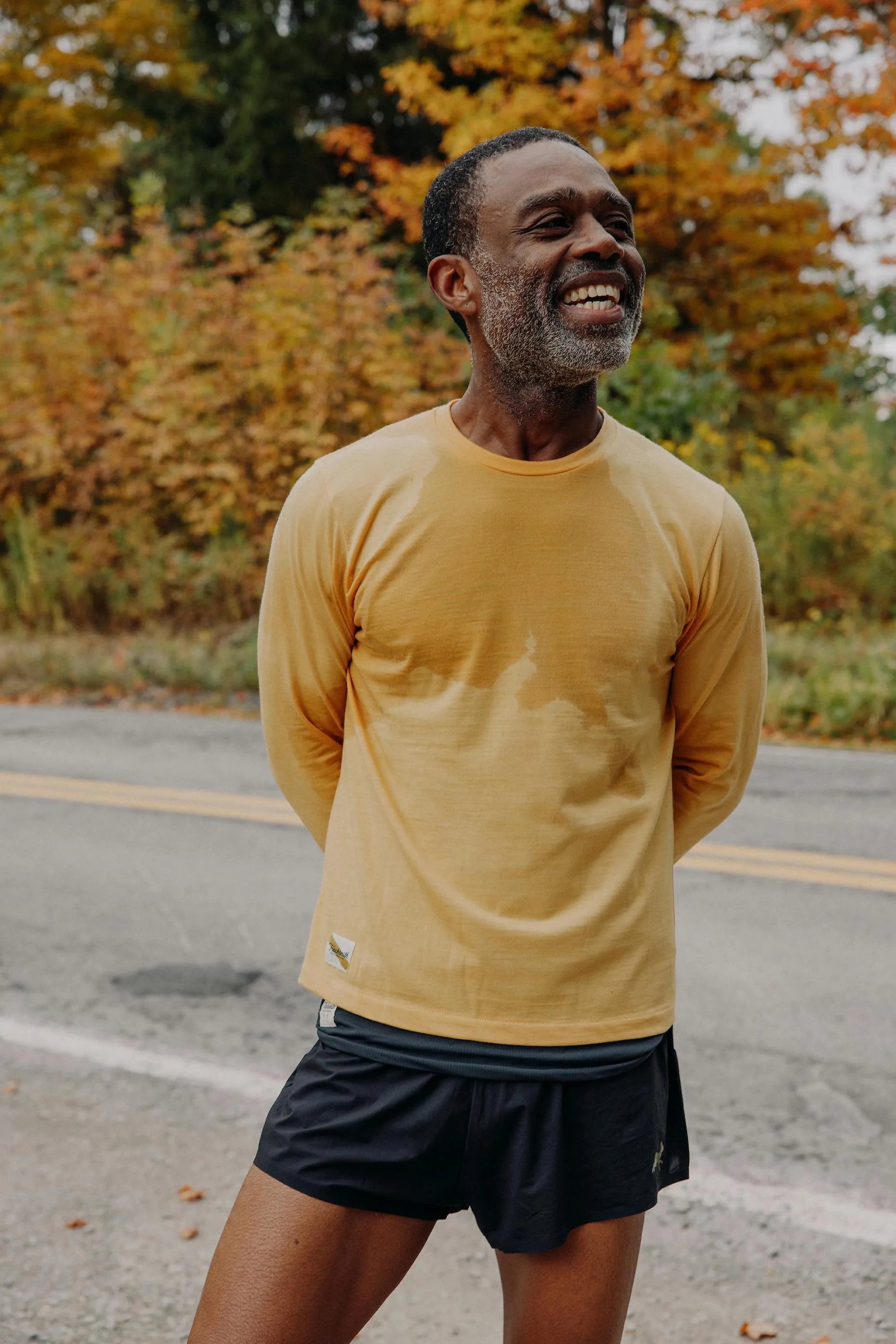 A smiling runner after a cold run, autumn trees behind