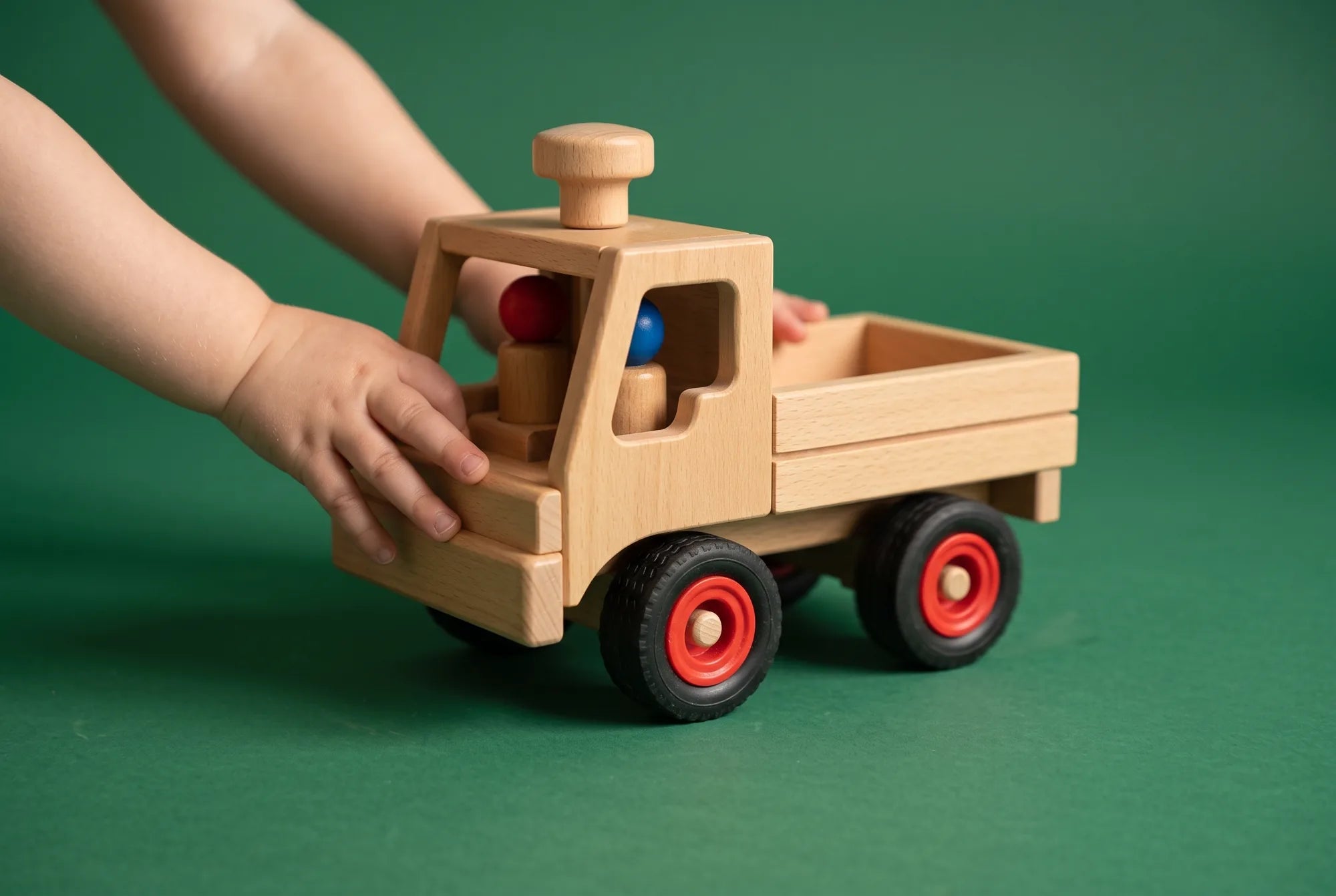 A toddler’s hands pushing the Fagus Unimog truck