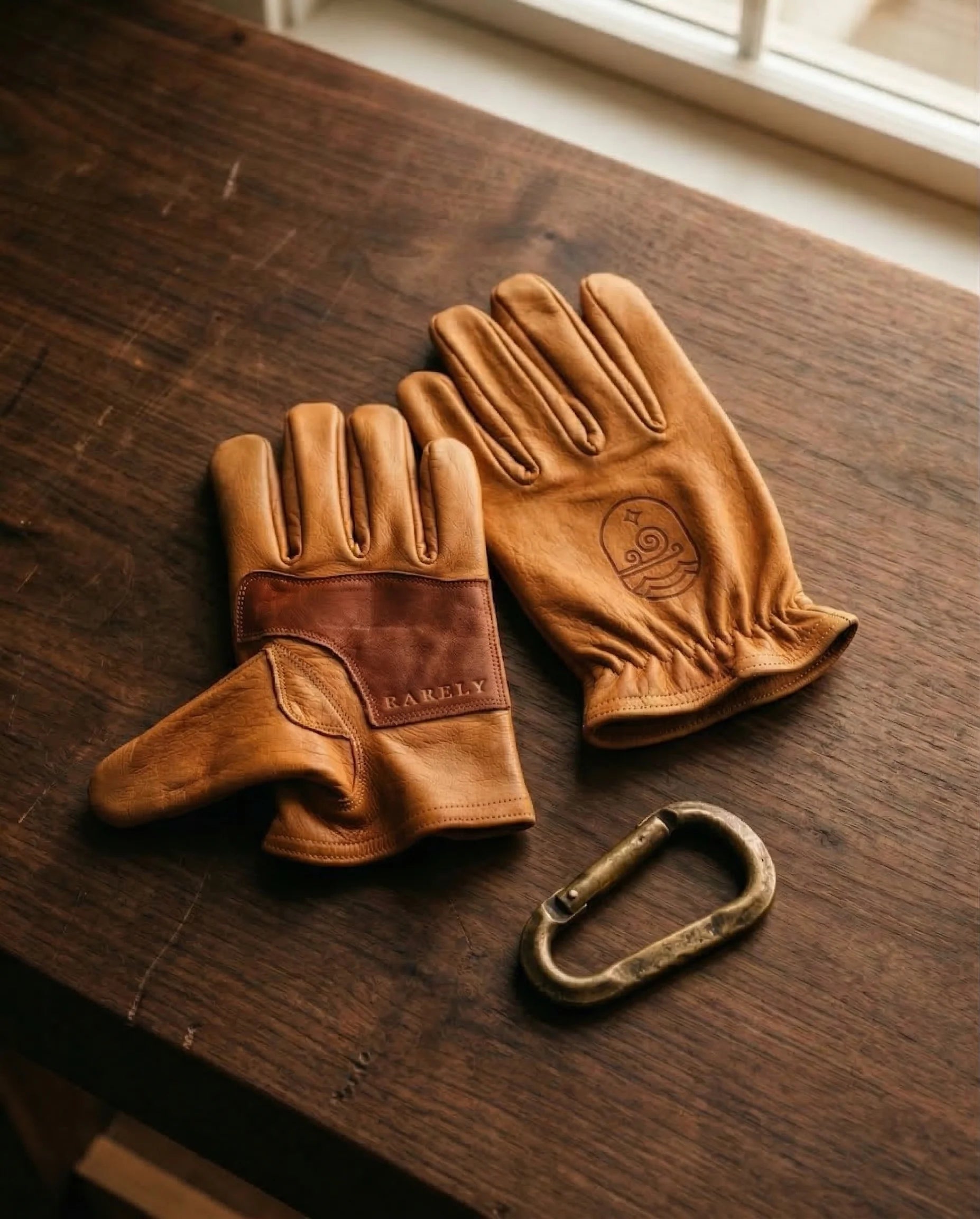 Brand-new saddle-tan buffalo leather gloves on a walnut workbench