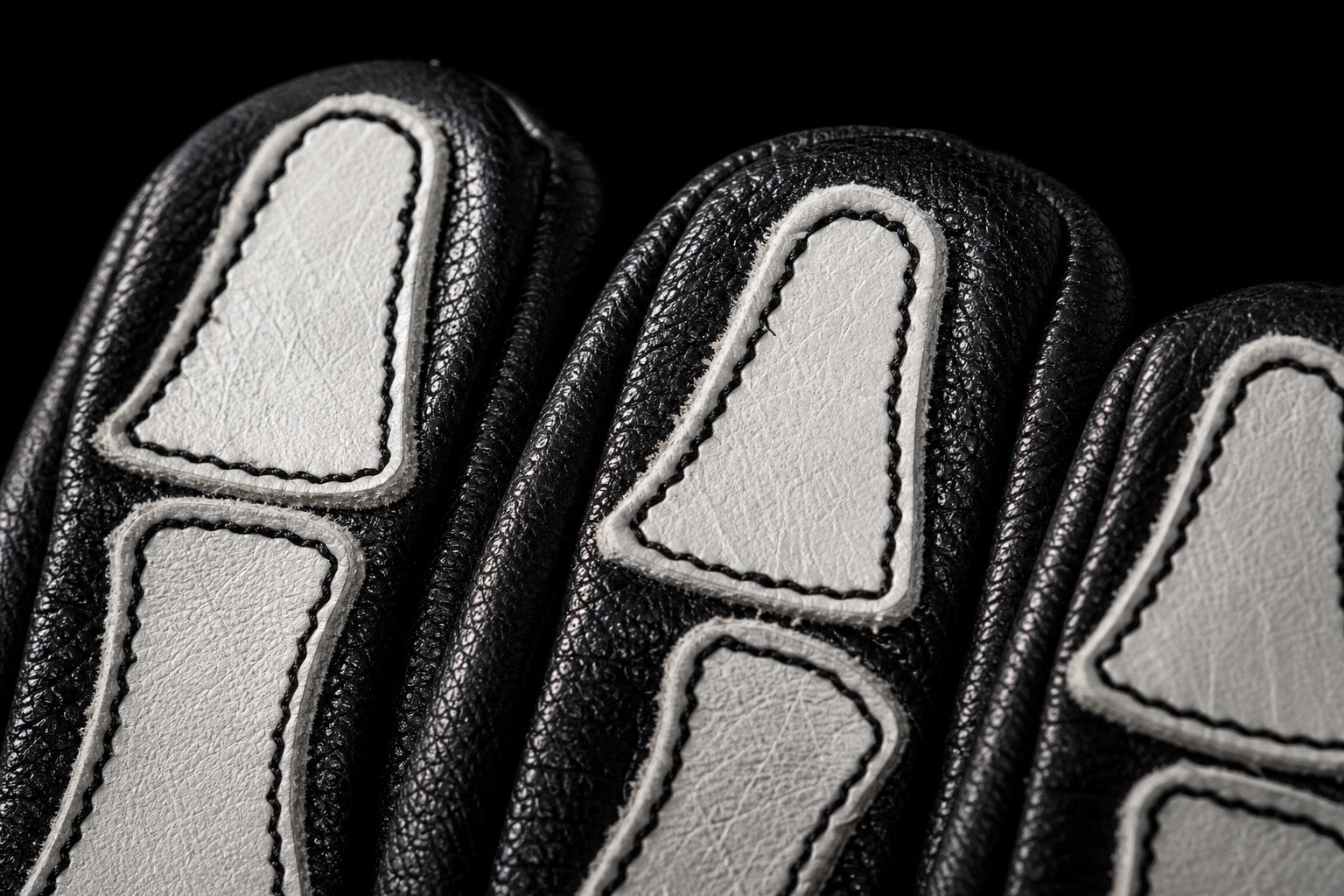 Extreme close-up of white bone panel stitching on black buffalo leather