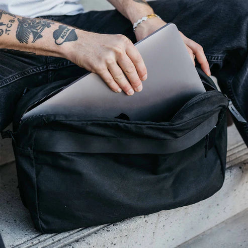 Laptop sliding into the spacious main compartment of the Canyon Crossbody Large